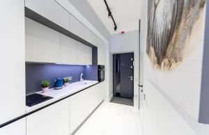 a kitchen with white cabinets and a blue wall at Fashionable apartments. Smartplaza metro Minskaya. Obolon in Kyiv