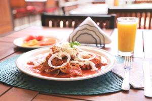 une assiette de nourriture sur une table avec un verre de jus d'orange dans l'établissement Hotel Casa de la Tía Tere, à Oaxaca