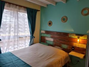 1 dormitorio con 1 cama con cabecero de madera y ventana en Cabañas Costa Norte, en Algarrobo