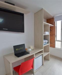 Habitación con escritorio, ordenador portátil y TV. en Hotel Bestmark Platino, en Bogotá