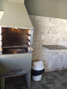 a kitchen with a grill with a trash can at Recanto Serra Negra - Sossego e lazer! in Serra Negra