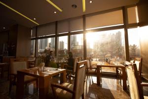 restauracja z drewnianymi stołami i krzesłami oraz dużym oknem w obiekcie Songdo Central Park Hotel w mieście Inczon