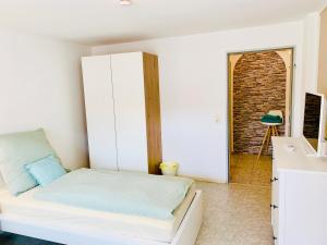 a small bedroom with a bed and a brick wall at Ferienwohnung Marie - WLAN, Küche, im Ortskern, Einkaufsläden in der Nähe in Malterdingen +7 photos