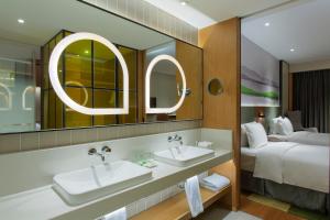 Holiday Inn & Suites Tianjin Downtown, an IHG Hotel في تيانجين: حمام الفندق مغسلتين وسرير