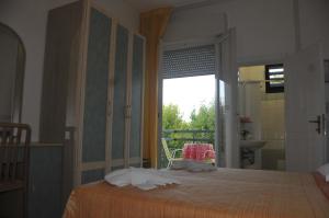 a bedroom with a bed and a window and a bathroom at Hotel Lux in Cesenatico
