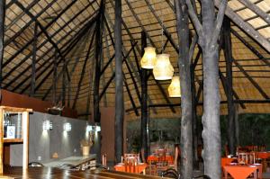 a restaurant with trees and tables and chandeliers at Munga Eco-Lodge in Livingstone