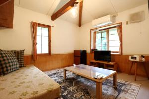 a living room with a couch and a coffee table at Pension Yasuda in Takayama