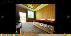 um quarto com uma cama e uma grande janela em Hotel Sarfaranga & Restaurant em Ranga