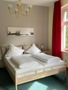 a bedroom with a bed with white sheets and a red curtain at Parkhotel Schnorr in Lutherstadt Eisleben