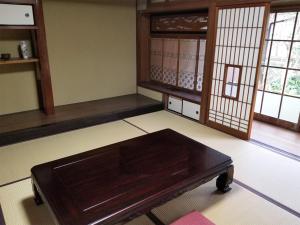 a living room with a wooden table and windows at コンドミニアム津和野荘 in Tsuwano