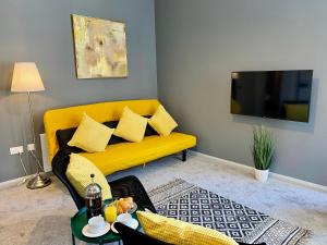 a living room with a yellow couch and a tv at Trendy Stylish Apartment! - 5 Minute Walk to the Best Beach! - Great Location - Parking - Fast WiFi - Smart TV - Newly decorated - sleeps up to 6! Close to Bournemouth & Poole Town Centre & Sandbanks in Bournemouth