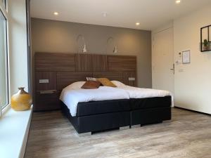 Schlafzimmer mit einem großen Bett mit einem Kopfteil aus Holz in der Unterkunft Hotel Café Restaurant De Ploeg in Varsseveld