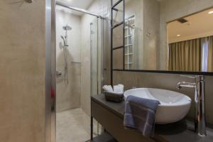 a bathroom with a tub, sink and mirror at Hotel @Syngrou Fix in Athens