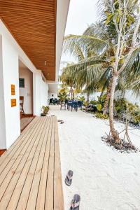 eine hölzerne Veranda mit einer Palme und Sandalen am Strand in der Unterkunft Island Zephyr in Baa-Atoll