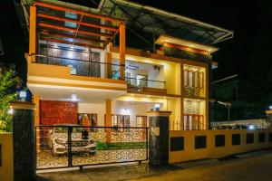 a large yellow house with a balcony at night at Belljem Homes -your own private resort -6 BHK S in Trichūr