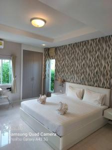 - une chambre avec un grand lit blanc et des serviettes dans l'établissement The Sept Korat, à Nakhon Ratchasima