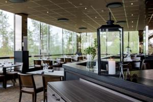 um restaurante com mesas, cadeiras e janelas em Lapland Hotels Sky Ounasvaara em Rovaniemi