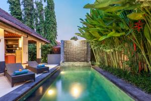 a swimming pool in a backyard with chairs and plants at Asrina Villa's Seminyak in Seminyak