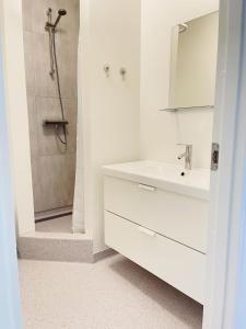 La salle de bains blanche est pourvue d'un lavabo et d'une douche. dans l'établissement aday - Aalborg mansion - Studio with terrace and garden, à Aalborg