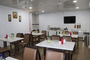 une salle à manger avec des tables et des chaises blanches dans l'établissement Hotel The Furat Inn, à Vapi