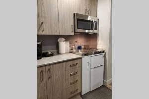 a kitchen with wooden cabinets and a sink and a microwave at Cozy Sweet Studio #4, Only 10 min to D.T. Ottawa in Gatineau