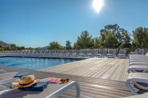 a pool with chairs and a table with a hat and sunglasses at SOWELL RESIDENCES Chênes Verts in Saint-Raphaël