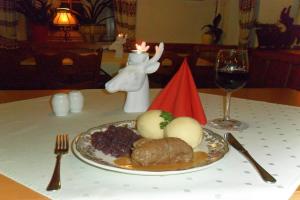 einen Teller mit Essen auf einem Tisch mit einem Glas Wein in der Unterkunft Hotel Hirsch in Seebach