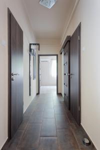 a hallway with wooden doors and a tile floor at Nimród Apartman in Eger