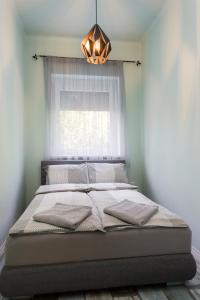 a bed in a bedroom with a window and a chandelier at Nimród Apartman in Eger
