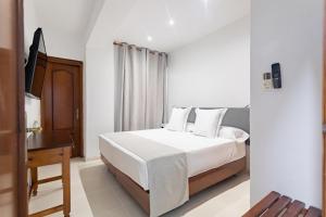 Habitación blanca con cama y escritorio en Hostal La Costa en El Ejido