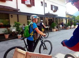 un hombre con una mochila de pie con una bicicleta en Gostišče Jazbec - Idrsko - Kobarid, en Kobarid
