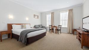 um quarto de hotel com uma cama, uma secretária e uma televisão em Lake Inn - Ballarat em Ballarat