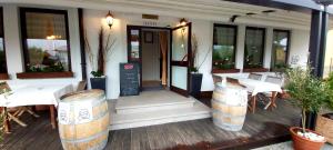 a restaurant with white tables and barrels in front of it at Gostišče Jazbec - Idrsko - Kobarid in Kobarid