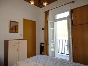 a bedroom with a bed and a door to a balcony at Kod Senke in Komiža