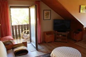 ein Wohnzimmer mit einem TV und einem Balkon in der Unterkunft Ferienwohnungen Bredl in Zwiesel