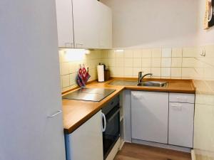 a small kitchen with white cabinets and a sink at Ferienwohnung Skowronek am Kurpark in Glücksburg