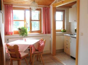eine Küche mit einem Tisch, Stühlen und Fenstern in der Unterkunft Ferienwohnungen Bredl in Zwiesel