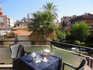 a table and chairs on a balcony with a palm tree at Le Perle in Bordighera