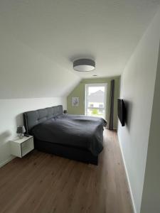 a bedroom with a black bed and a window at Wangerbrise in Wangerland