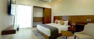 a bedroom with a bed and a desk and a chair at GG HOTELS in Tiruppūr