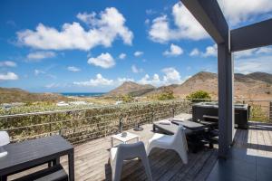 einen Balkon mit einem Tisch, Stühlen und einem Grill in der Unterkunft The Rock in Saint Martin