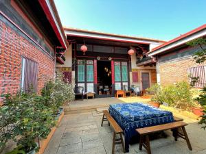 a patio with a table and a bench in front of a building at Grace Kinmen B&B in Jincheng