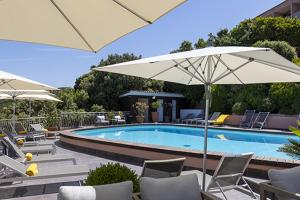 a swimming pool with chairs and umbrellas next to at Hôtel Capo Rosso in Piana