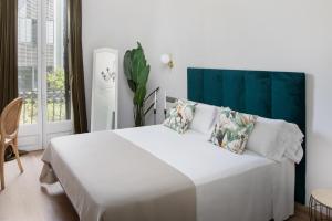 una camera bianca con un grande letto bianco con cuscini di La Maison de Barcelone a Barcellona