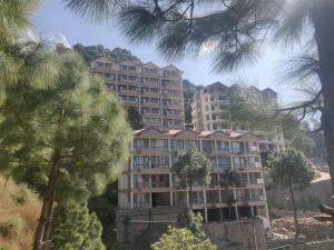 a building with palm trees in front of it at Nature, Meditation with fun and Luv in Woods BAROG near KASAULI in Barog