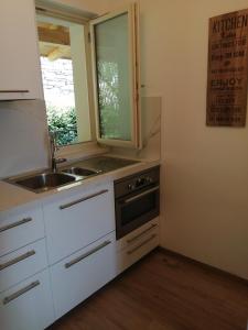 kuchnia z białymi szafkami, umywalką i oknem w obiekcie Lattementa w mieście Verbania