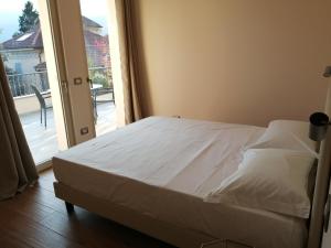 białe łóżko w pokoju z przesuwanymi szklanymi drzwiami w obiekcie Lattementa w mieście Verbania