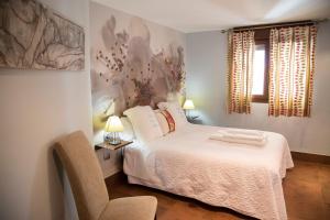 a bedroom with a white bed and a chair at Palacio Sirvente Mieres - PARKING GRATUITO in Andújar