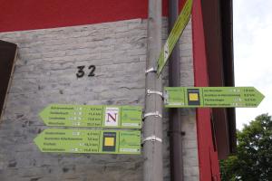 un poteau avec panneaux de signalisation devant un bâtiment dans l'établissement Gaestehaeuser Am Nibelungensteig, à Lautertal
