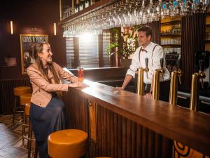 Ein Mann und eine Frau stehen an einer Bar in der Unterkunft Plopsa Hotel in De Panne